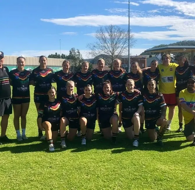 The Panthers women's team lines up for a photo on the field in black, green, gold and red jerseys